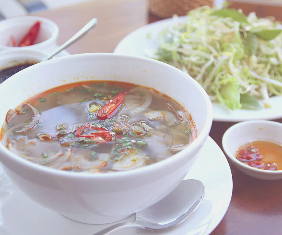 Plate with soup, in the background plate with salad, bowl with hot sauce