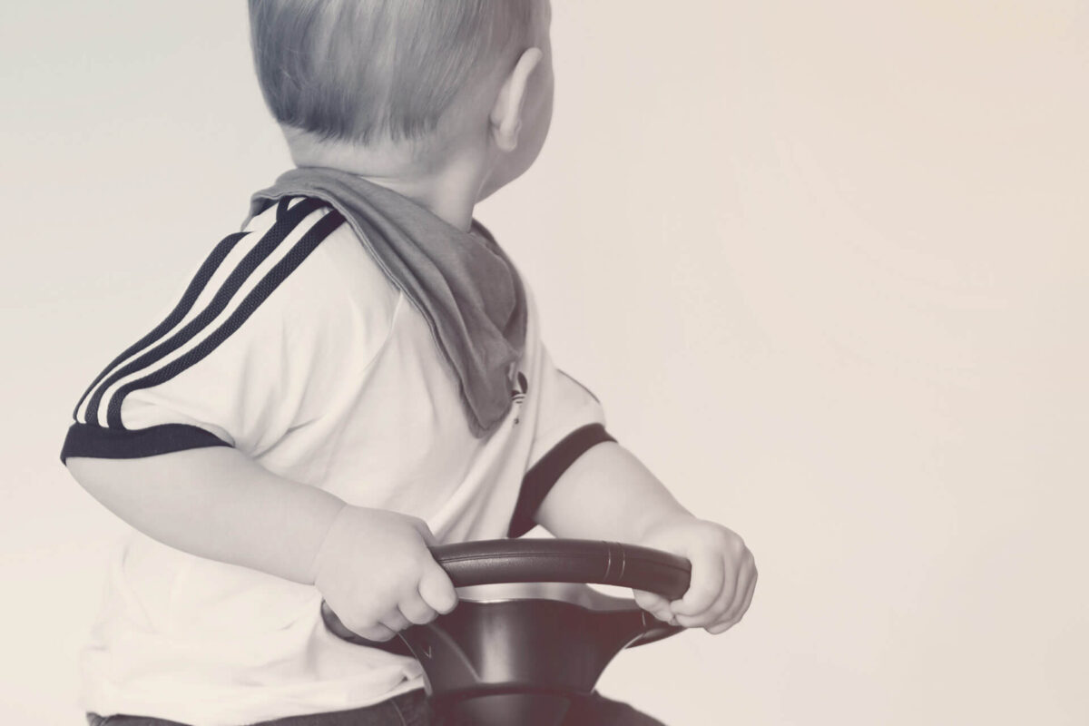 Niño sentado en vehículo de juguete y mirando hacia atrás